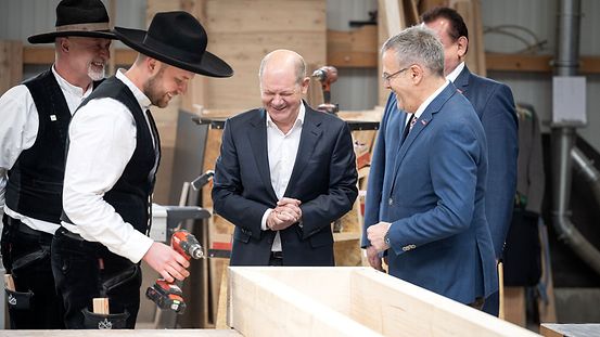 Zwei Mitarbeitende der Firma Lepski GmbH zeigen dem Bundeskanzler wie die Holzbaumodule fertiggestellt werden,