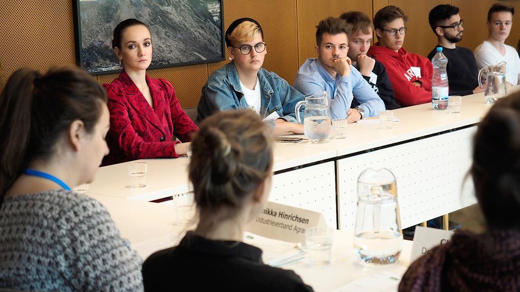 Jugendliche halten eine Sitzung des Planspiels im Bundesumweltministerium ab. Ihnen gegenüber sitzen drei Referentinen, die in die Rollen der Verbandsvertreterinnen geschlüpft sind.
