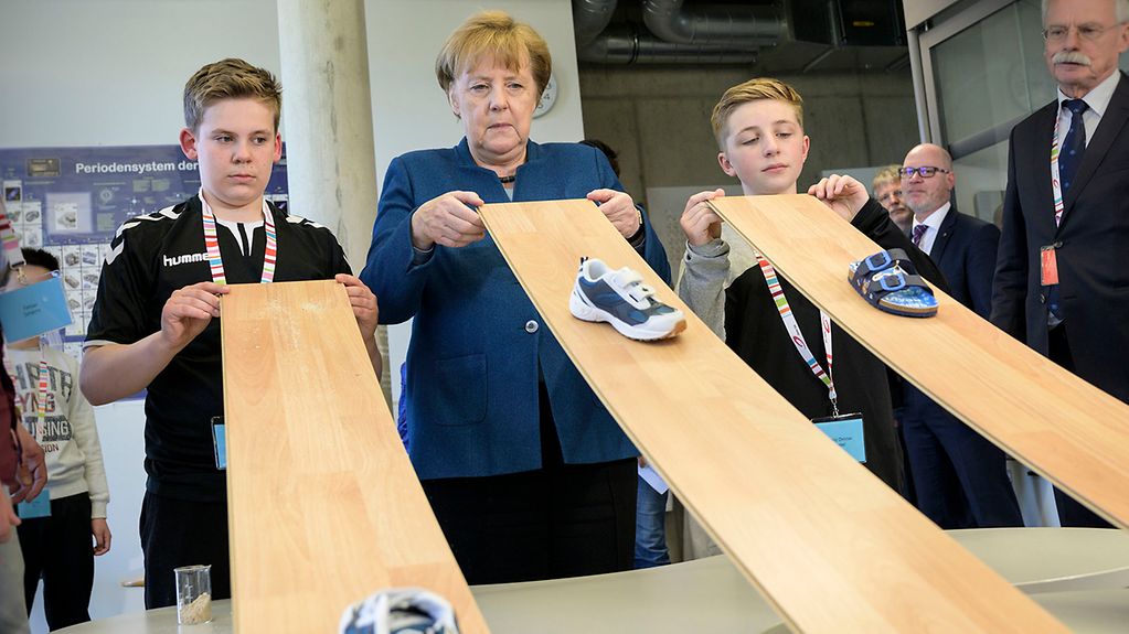 Chancellor Angela Merkel gets involved in an experiment during her visit to the Junior University in Wuppertal.