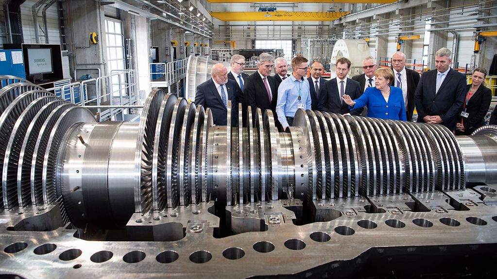 Angela Merkel wird eine Turbine in den Werkshallen des Dampfturbienenherstellers Siemens präsentiert.