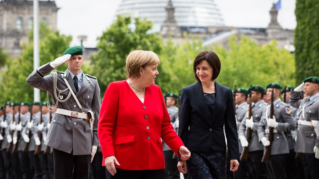 Angela Merkel und Ministerpräsidentin Maia Sandu gehen über den roten Teppich.