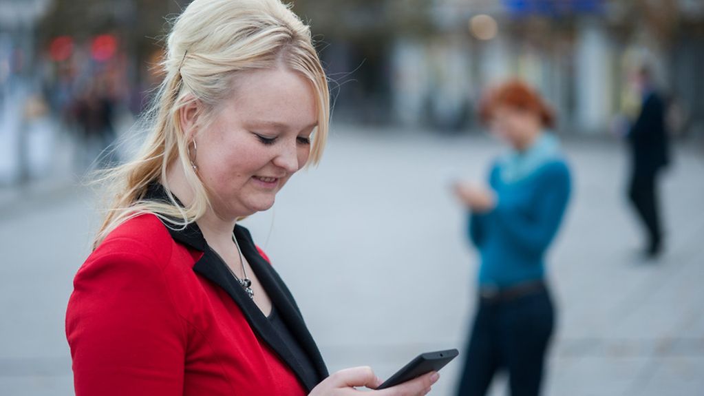 Eine junge Frau surft mit ihrem Handy im Internet.