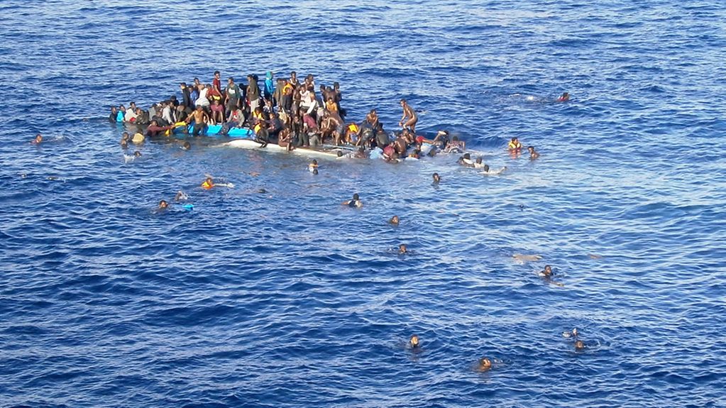 Refugees cling to a capsized vessel in the Mediterranean