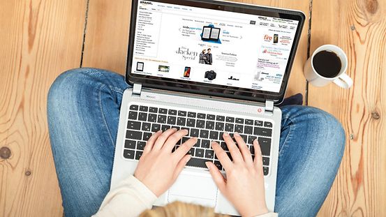Eine Frau kauft mit ihrem Laptop auf dem Schoß auf einer Online-Shopping-Seite ein.
