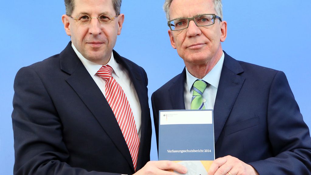 Der Präsident des Bundesamtes für Verfassungsschutz, Massen (l), und Bundesinnenminister de Maiziere halten zusammen den Verfassungsschutzberichts 2014.