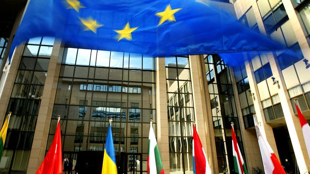 Le 16 juin 2004, les drapeaux des États membres de l’Union européenne ornent l’entrée du bâtiment Justus Lipsius, siège du Conseil de l’Union européenne à Bruxelles. Les chefs d’État ou de gouvernement sont résolus à trouver un accord.
