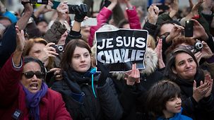 Eine Demonstrantin hält ein Schild "Je Suis Charlie".