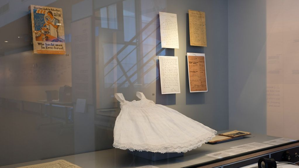 In einer Ausstellungsvitrine sind historische Dokumente und Kleidung zu sehen.