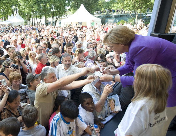Bundeskanzlerin Merkel gibt einem Besucher ein Autogramm