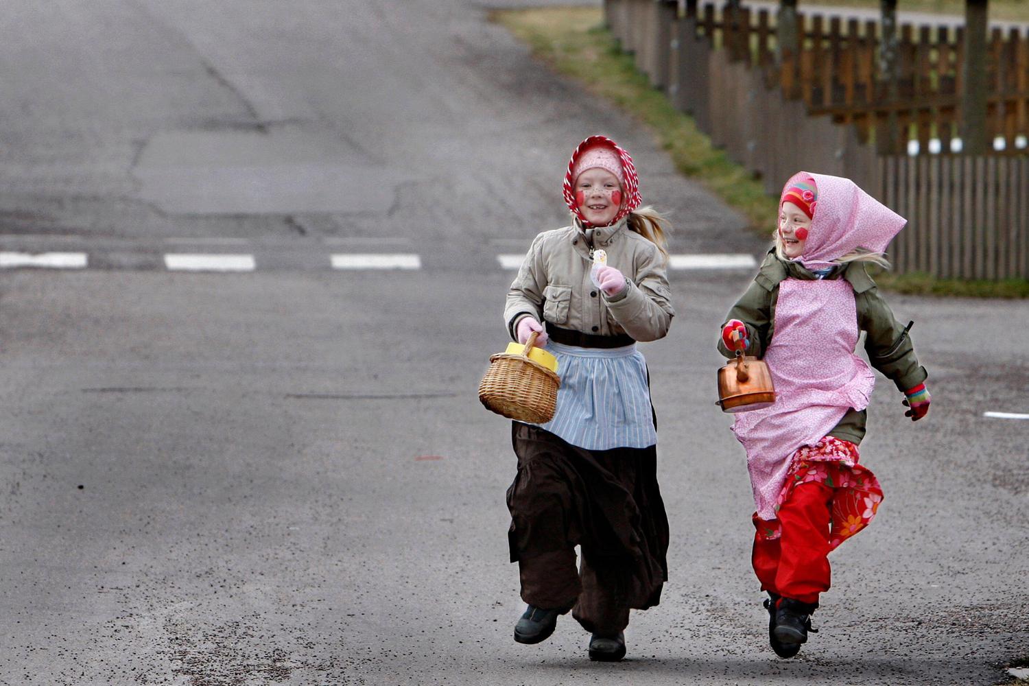 Zwei als Hexen verkleidete Mädchen laufen durch eine Straße in Schweden.