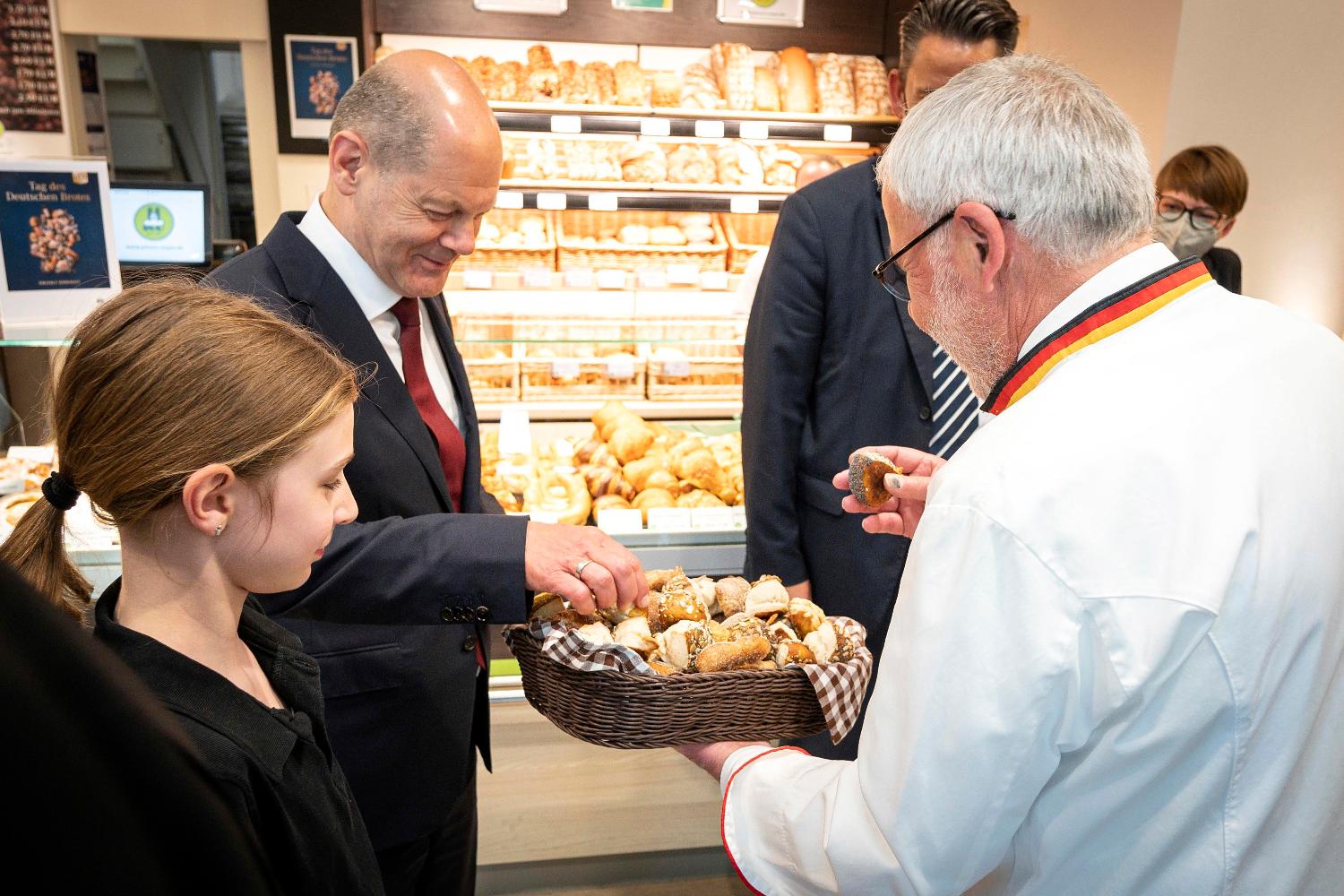 Bundeskanzler Scholz greift in einem kleinen Brotkorb, in einer Bäckerei