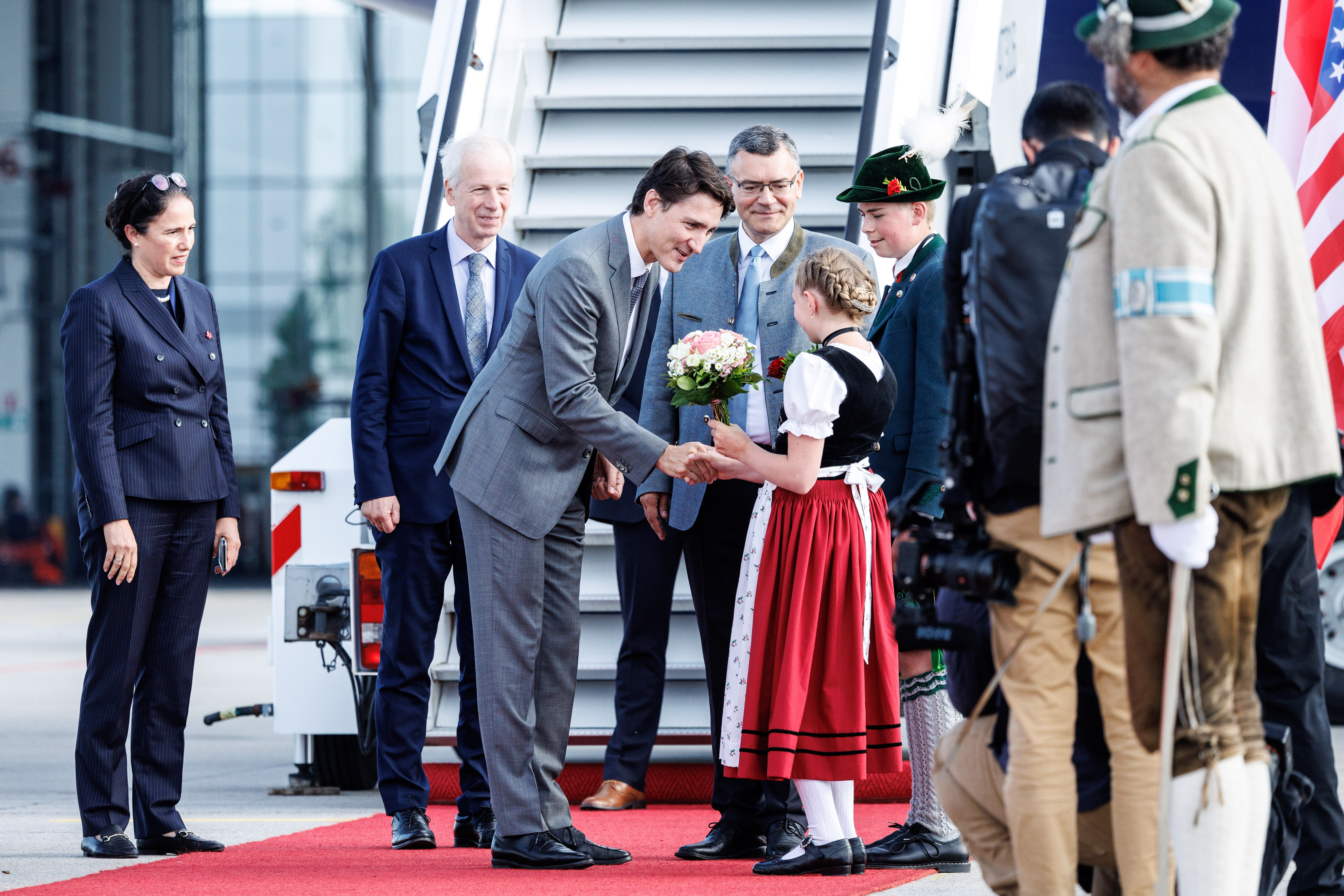Mit einem Blumenstrauß wird Justin Trudeau, Premierminister Kanadas, von einem Mädchen in Tracht begrüßt.