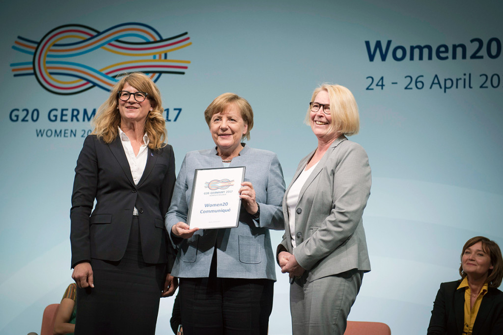 Chancellor Angela Merkel (centre, holding the communiqué) with Mona Küppers, President of the National Council of German Women's Organisations, and Stephanie Bschorr, President of the Association of German Women Entrepreneurs, at the W20 summit