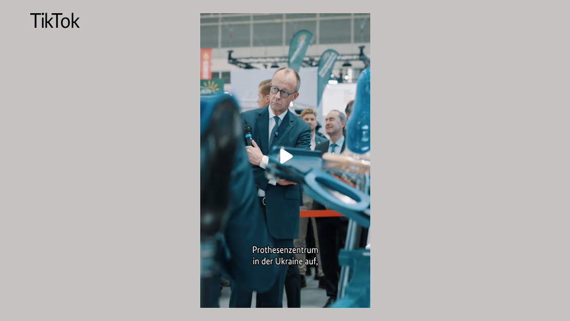 Kanzler Merz mit einem Mikrophon in der Hand auf der Handwerksmesse. Im Hintergrund weitere Personen, im Vordergrund sind medizinische Prothesen zu erkennen.