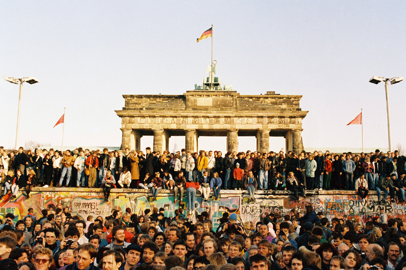 Am 9. November 1989 öffnet die DDR ihre Grenze nach Westberlin und zur Bundesrepublik; nach 28 Jahren fällt die Mauer. Bewohner aus West- und Ostberlin stehen am 10.11.89 auf der Mauerkrone am Brandenburger Tor.