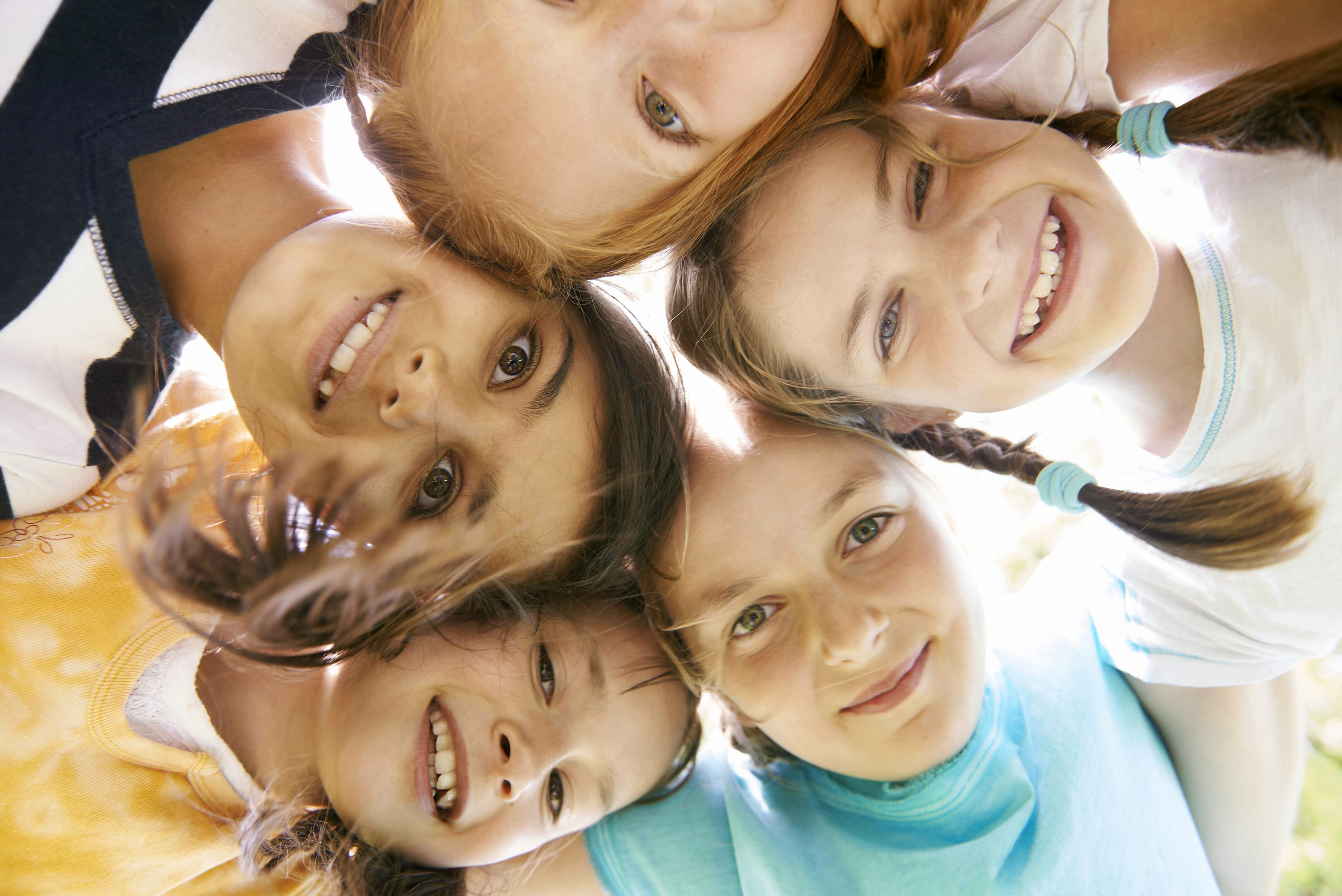Fröhliche Kinder stecken die Köpfe zusammen und lachen gemeinsam.