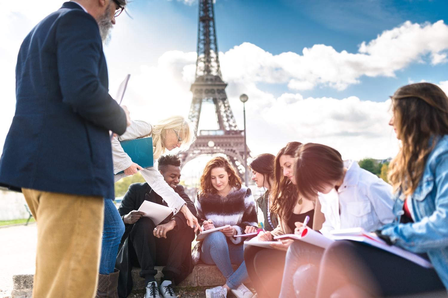 Studenten sitzen in einer Lerngruppe nahe des Eiffelturms.