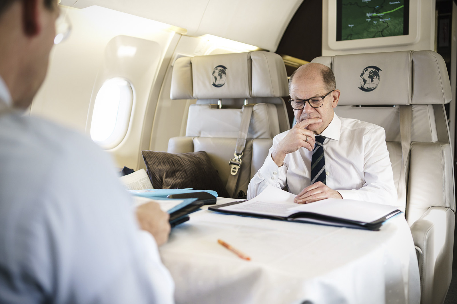 Bundeskanzler Olaf Scholz liest im Flugzeug.
