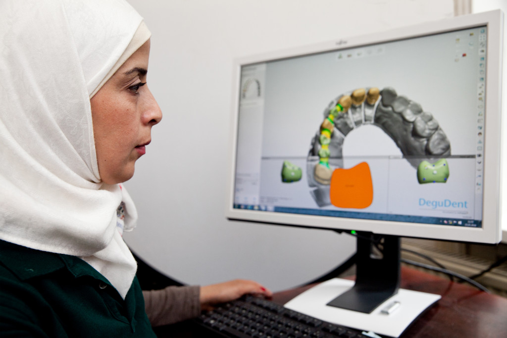 Wessal Alkhalil, Zahntechnikerin in Hamburg, sitzt vor einem Computer mit 3D-Animation eines Unterkiefers.