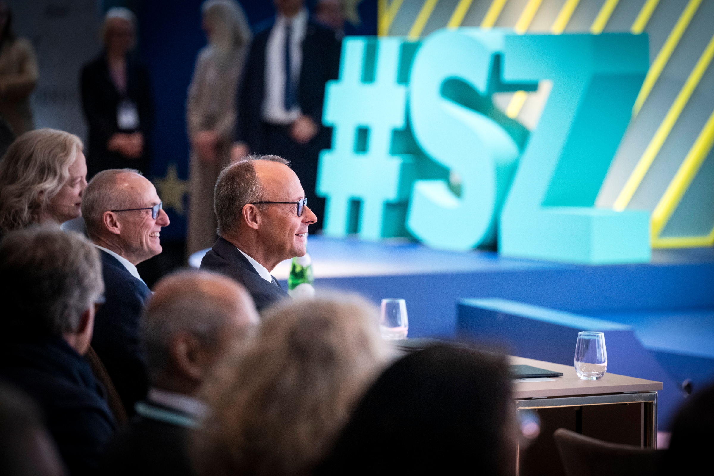 Das Foto zeigt Bundeskanzler Friedrich Merz im Publikum beim SZ-Wirtschaftsgipfel.