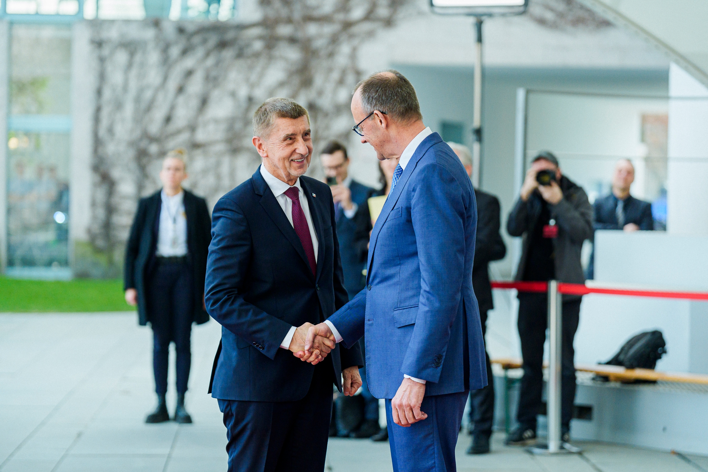 Bundeskanzler Friedrich Merz begrüßt Andrej Babiš, Tschechiens Ministerpräsident, mit einem Handschlag. Im Hintergrund verschwommen Fotographen und weitere Personen.