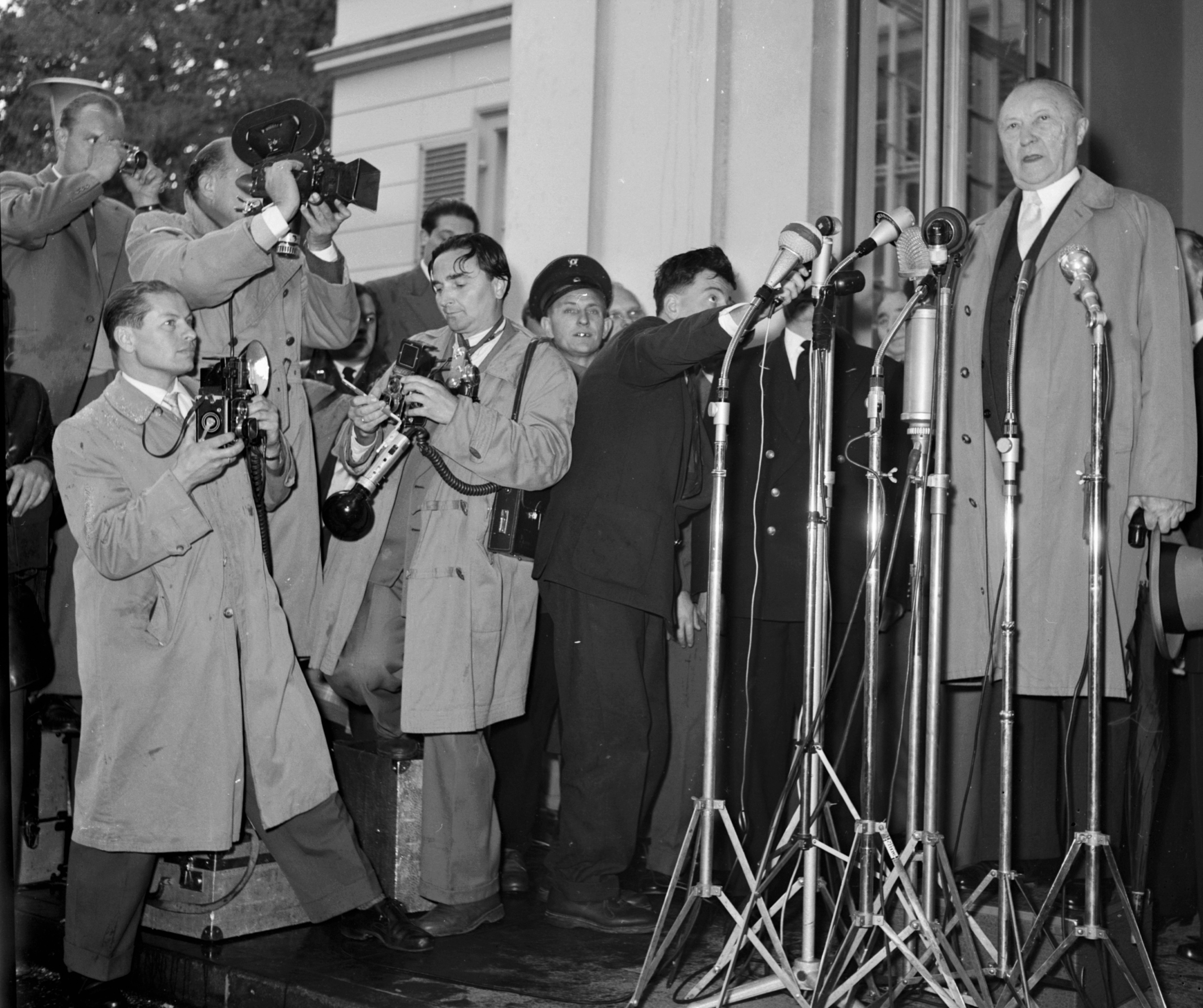 Schwarz-weiß-Fotografie zeigt Bundeskanzler Konrad Adenauer im Jahr 1957 bei einem Pressestatement.