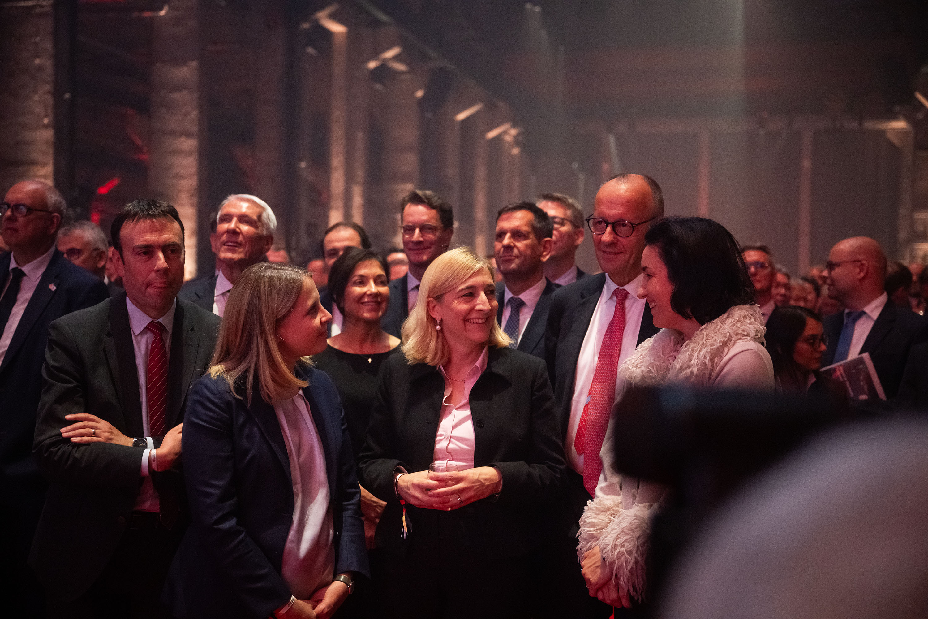 Bundeskanzler Friedrich Merz beim Auftakt zum Investitionsgipfel in einer Gruppe von Teilnehmerinnen und Teilnehmern.