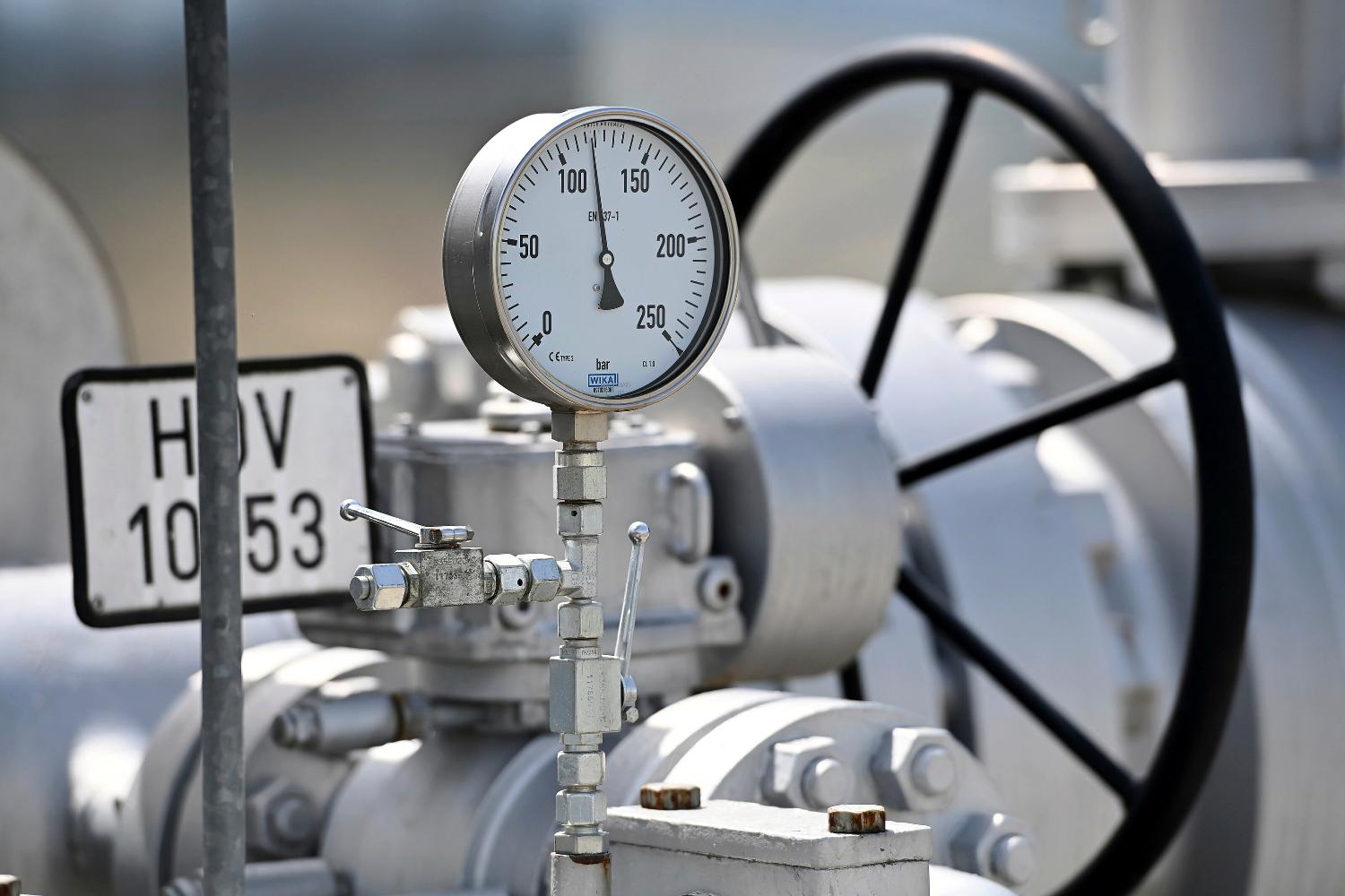 The image shows a gas cylinder and a pressure gauge. The needle indicates a medium level.