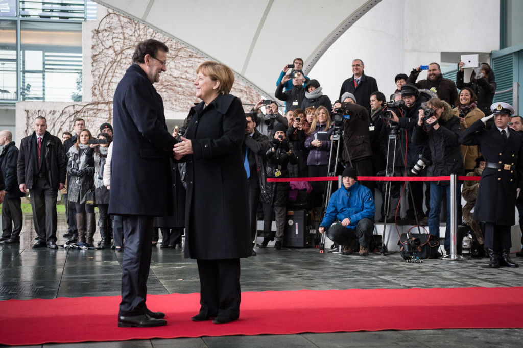 Angela Merkel welcomes Mariano Rajoy in front of a group of journalists.