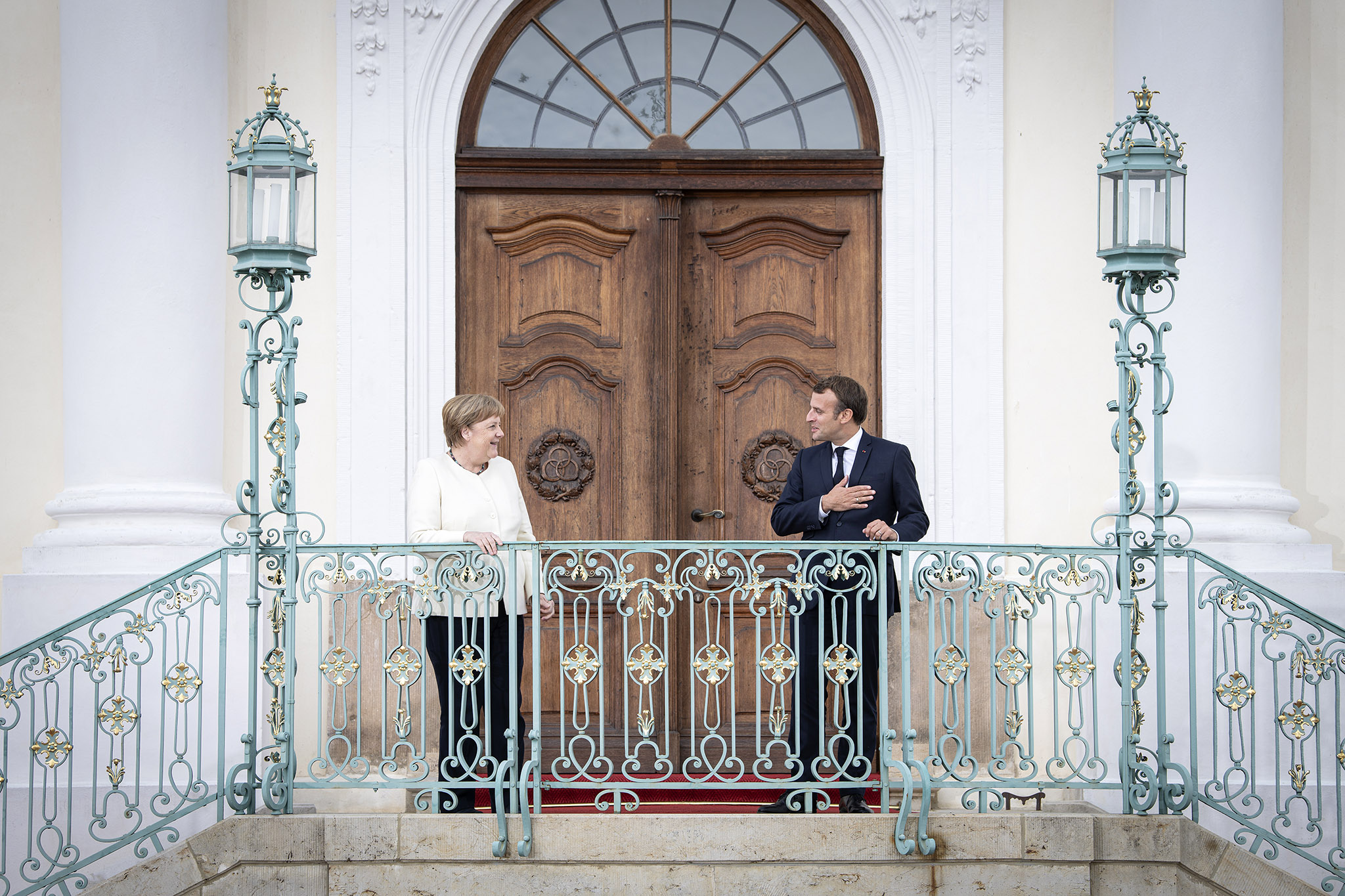 Federal Chancellor Merkel and President Macron in front of a door.