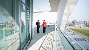 Chancellor Angela Merkel and French President Emmanuel Macron in conversation on one of the terraces of the Federal Chancellery