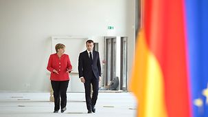 Bundeskanzlerin Angela Merkel und Frankreichs Präsident Emmanuel Macron gehen durch den Rohbau des Humboldtforums.
