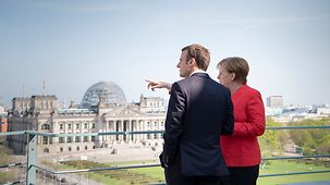 Bundeskanzlerin Angela Merkel und Frankreichs Präsident Emmanuel Macron blicken von einer Terrasse des Bundeskanzleramtes über das Regierungsviertel.