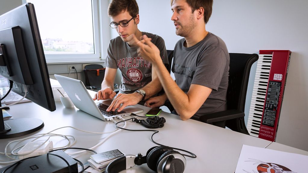 Team von zwei jungen Männern diskutiert vor einem Computer Geschäftsmodelle