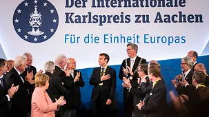 French President Emmanuel Macron, winner of this year's Charlemagne Prize, surrounded by guests following the award ceremony