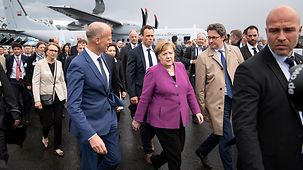 Bundeskanzlerin Angela Merkel geht - unter anderem mit Andreas Scheuer, Bundesminister für Verkehr und digitale Infrastruktur, über das Messegelände der ILA.