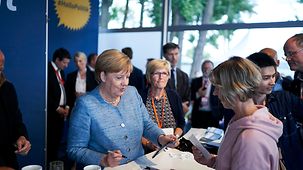 Bundeskanzlerin Angela Merkel schreibt Autogramme.