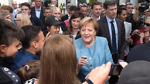 Bundeskanzlerin Angela Merkel schreibt beim Rundgang zum Tag der offenen Tür Autogramme.