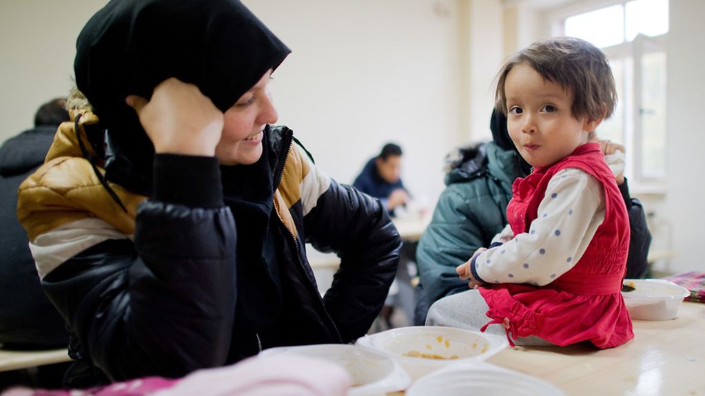 Ein zweijähriges Flüchtlingsmädchen aus Afghanistan sitzt mit ihrer Mutter in der Flüchtlingsunterkunft.