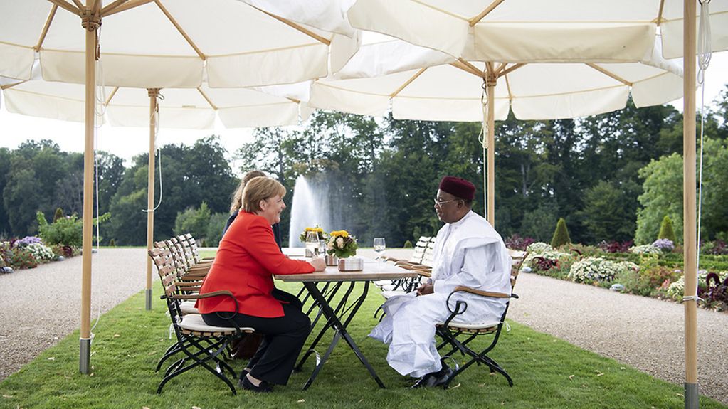 Bundeskanzlerin Angela Merkel und der Präsident der Republik Niger, Issoufou Mahamadou, während eines Gesprächs im Park von Schloss Meseberg.