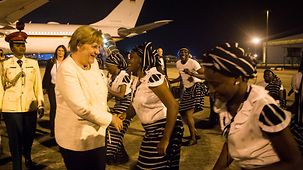 Chancellor Angela Merkel is welcomed on her arrival at Abuja Airport.