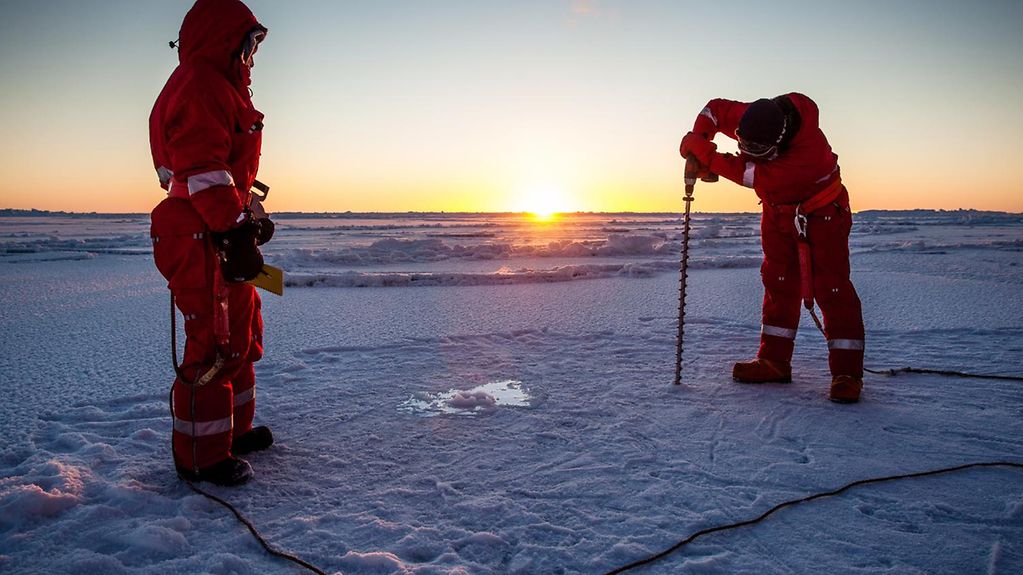 Zwei Forscher nehmen Eisbohrungen in der Arktis vor, um die Meereisdicke zu bestimmen.