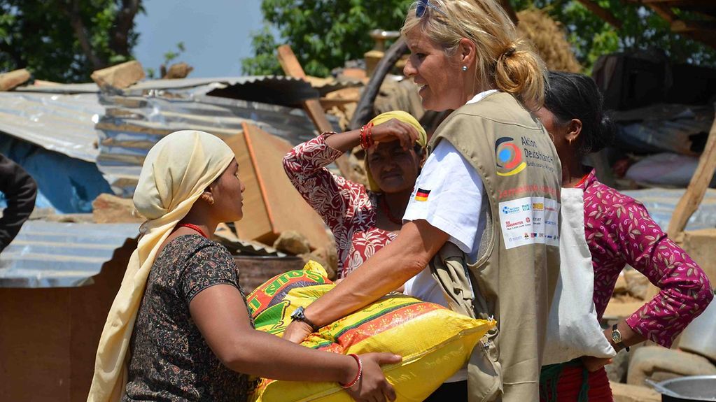 Ein Helferin der Bündnis "Aktion Deutschland hilft" überreicht einer nepalesischen Frau ein Hilfspaket.