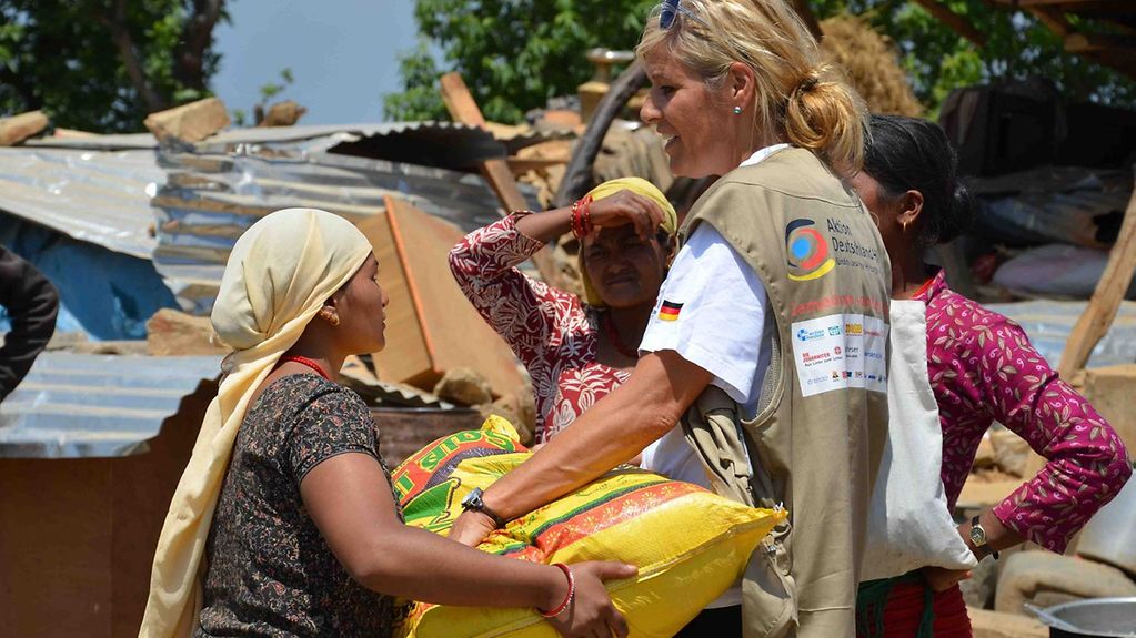 A helper working for Germany's relief coalition "Aktion Deutschland hilft" gives an aid package to a Nepalese woman.