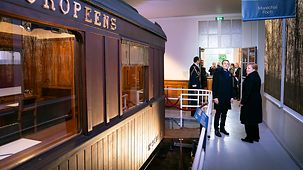 Bundeskanzlerin Angela Merkel und Frankreichs Präsident Emmanuel Macron stehen in einem Museum vor dem Nachbau des Waggons, in dem der Waffenstillstand des Ersten Weltkrieges unterzeichnet wurde.