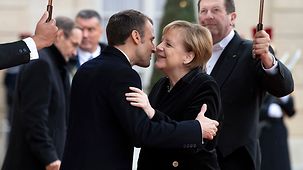 French President Emmanuel Macron greets Chancellor Angela Merkel.