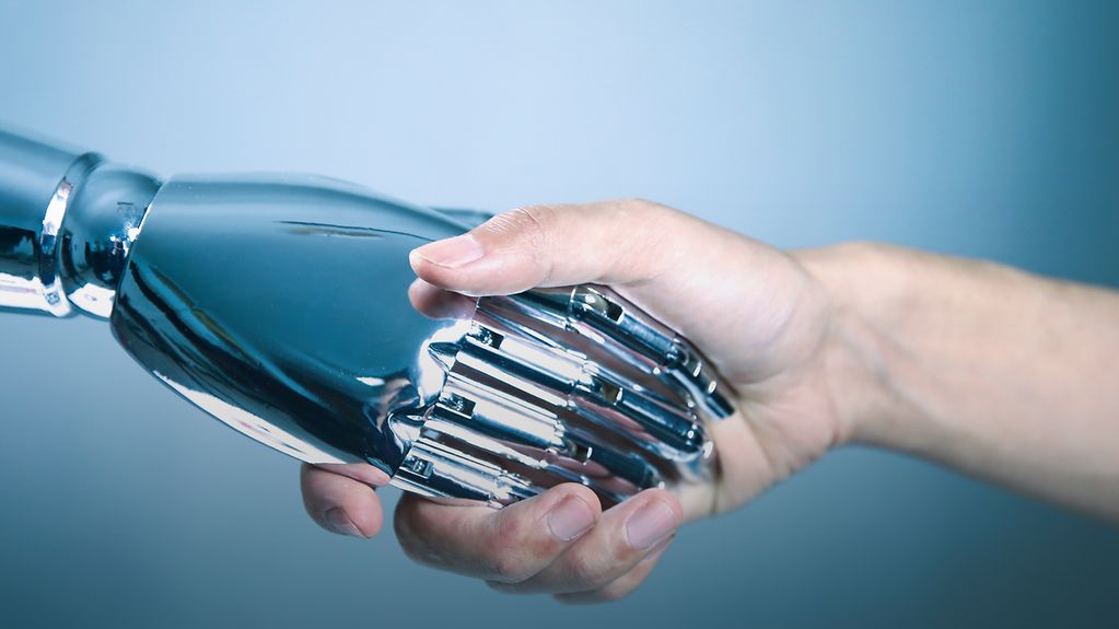 Une main robotisée serre une main humaine