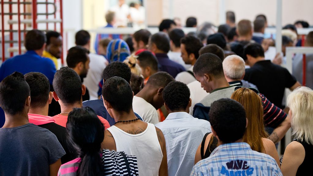Des demandeurs d’asile font la queue dans une administration afin d’obtenir des documents