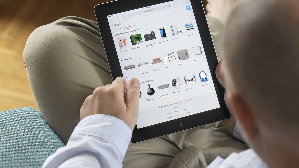 Ein Mann scrollt auf einem iPad durch die Shopping-Seite bei Google.