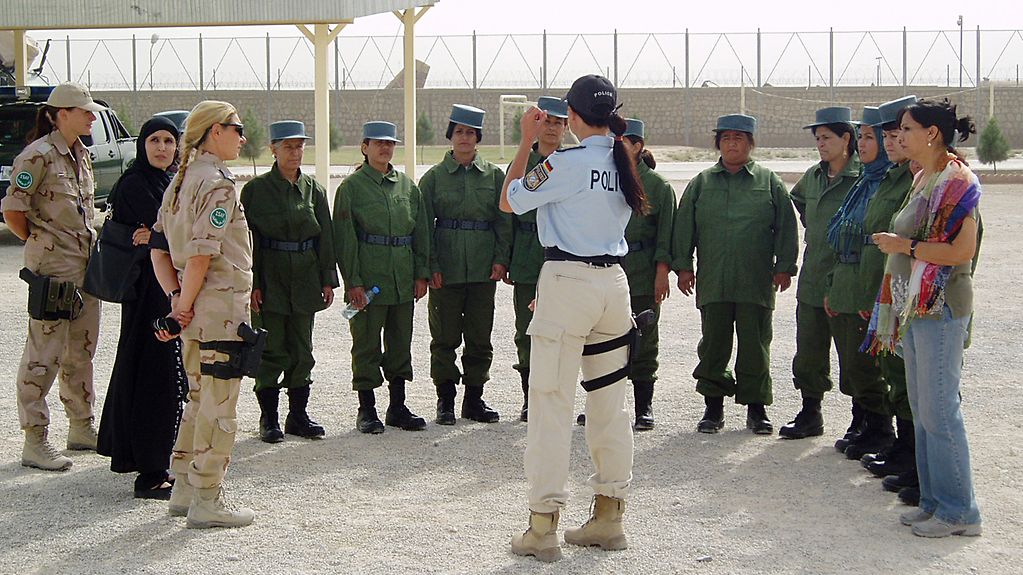 Deutsche Polizistin steht gestikulierend vor einem Kreis afghanischer Polizeikräfte.